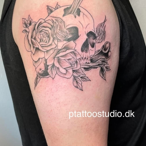 Kranier og blomster tatoveret på overarmen, lavet af P Tattoo Studio i Ikast