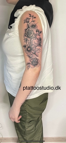 Tatovering af blomster og ur på overarmen lavet af P Tattoo Studio i Ikast