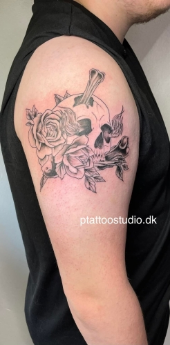 Kranier og blomster tatoveret på overarmen, lavet af P Tattoo Studio i Ikast